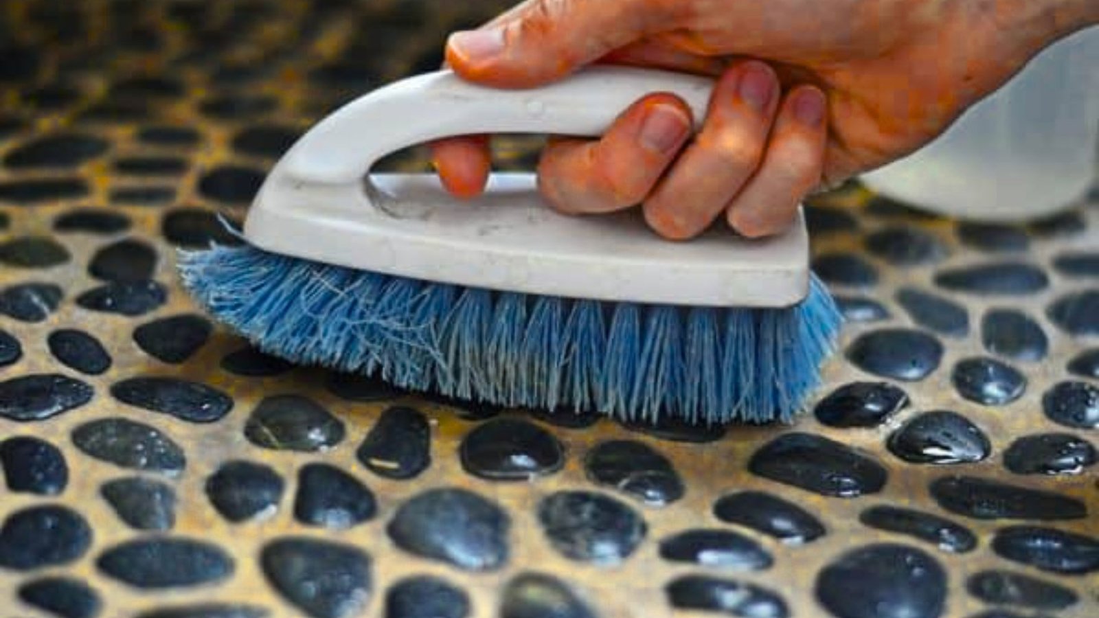 Picture showing cleaning of river rock shower floor.